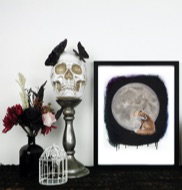 A realistic painting of a fox sitting in front of a full moon framed in a black frame sitting on a black table.